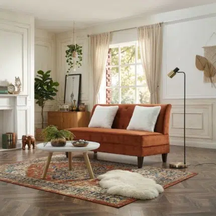 Rust orange 2 seater armless velvet sofa with tufted back, tapered wooden legs and white cushions in a bright modern living room UAE