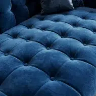 Luxury deep blue velvet lounge sofa with tufted design and chaise extension in modern marble interior living room UAE